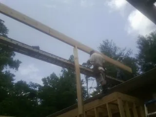 Carpenter setting a ridge beam over a new addition frame — Ice Dam Removal by Roofing Brothers in North Rose