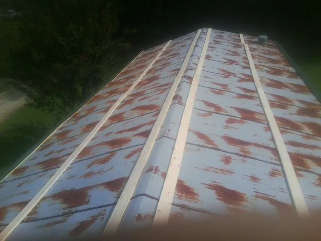 Rusted metal roof panels with new wood purlins before replacement — Storm Damage Roof Repair in North Rose by Roofing Brothers