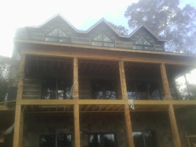 Dormers and porch framing on a large log home under construction — Roof Coating work by our crew in North Rose