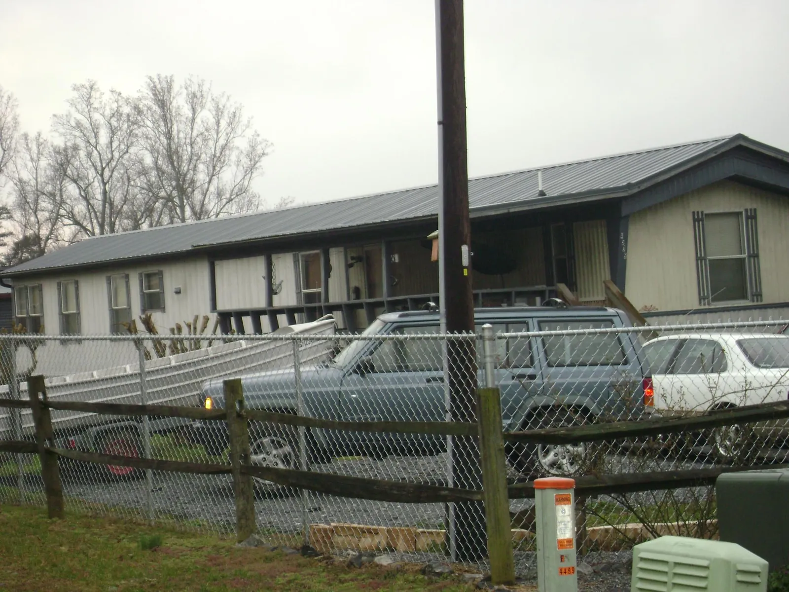 Dark metal roof on a long single story building behind a chain link fence in North Rose