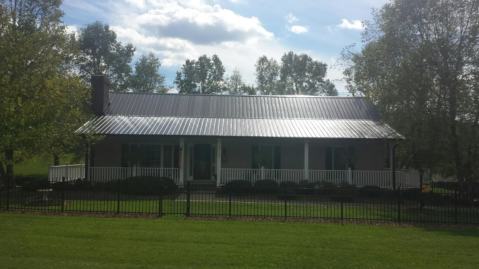 Gray metal roof on a brick ranch with a full width front porch — Gutter Guard Installation work by our crew in North Rose