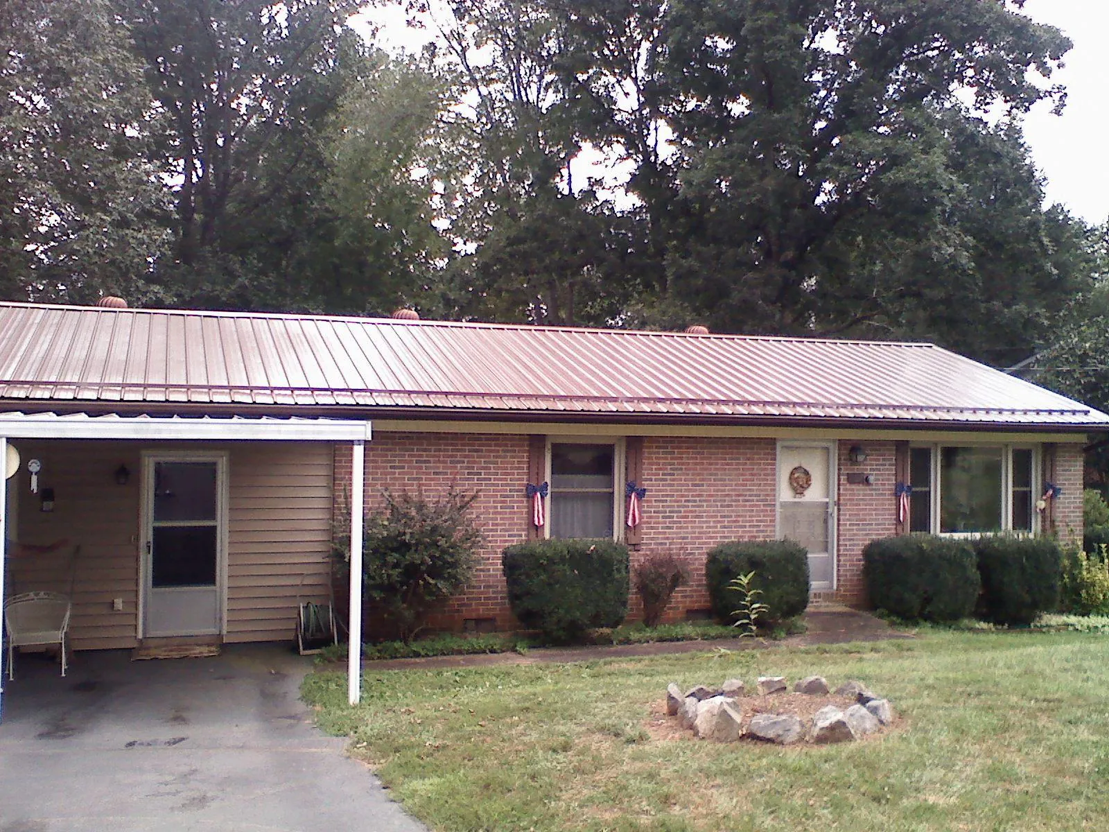 Bronze metal roof and carport on a brick ranch home — Roof Repair work by our crew in North Rose