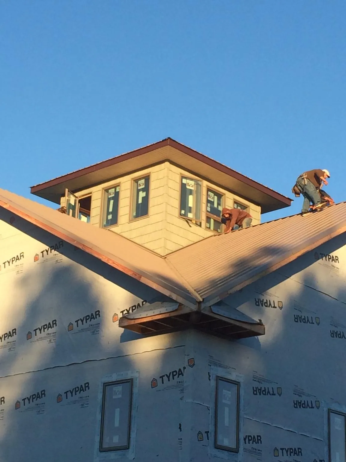 Roofers working around a rooftop cupola on a new metal roof at sunset — Roof Waterproofing in North Rose by Roofing Brothers